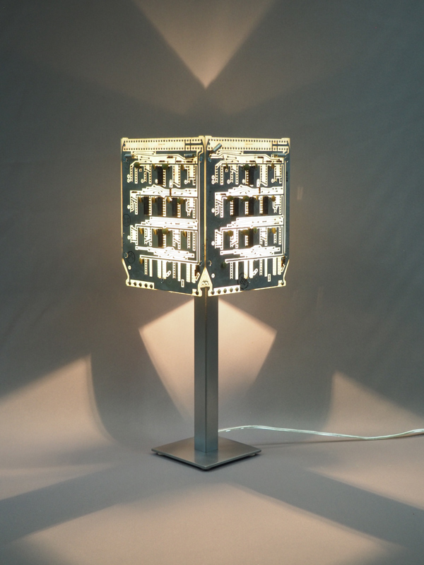 Lampe aspect argenté allumée acier brossé et cartes électroniques avec ses reflets