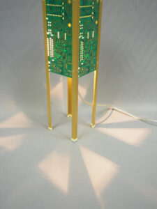Vue bas lampe verte et dorée allumée et réalisée avec des circuits imprimés. Piètement laitonné 4 pieds avec ses reflets