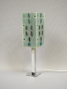 Lampe verte et argentée éteinte réalisée avec des cartes électroniques et un piètement en acier chromé