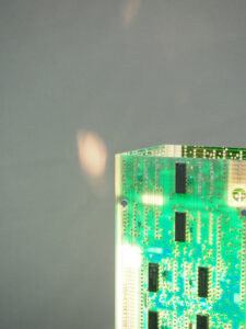 Vue dessus lampe verte et argentée allumée réalisée avec des cartes électroniques et un piètement en acier chromé avec ses reflets